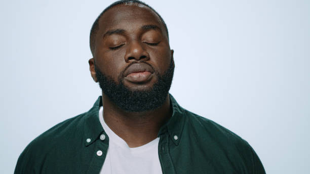 istock Close up sick african american man sneezing on grey background in studio. 1358155955