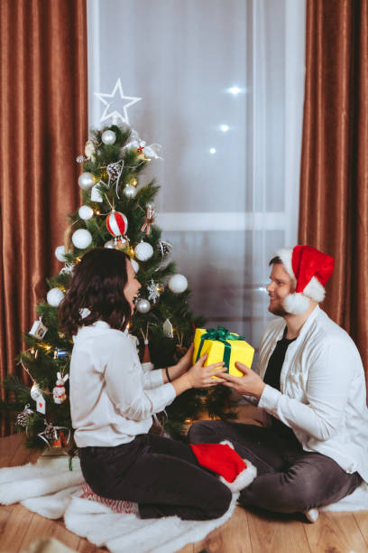 istock couple shooting in front of decorated christmas tree 1358158501
