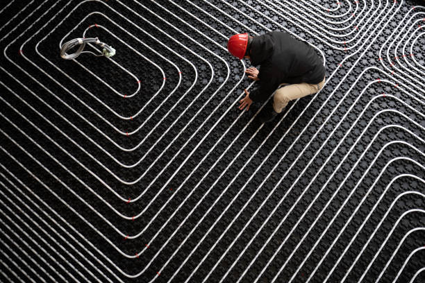 Worker adjusting position of pipes, diagonally oriented pattern on tubes Installing heating system in building. Worker adjusting position of pipes. Diagonally oriented pattern on tubes. Construction of modern family house. piping hot stock pictures, royalty-free photos & images