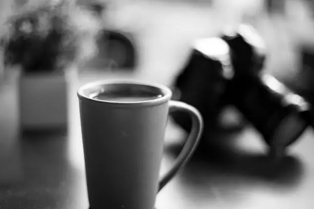 Photo of Cup of coffee on a coffee table along with a DSLR camera