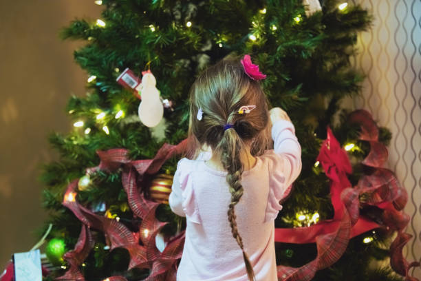 istock Girl Decorates Christmas Tree 1358168333