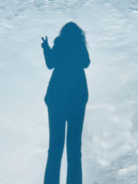 Winter Shadow of a woman making peace sign. stock photo