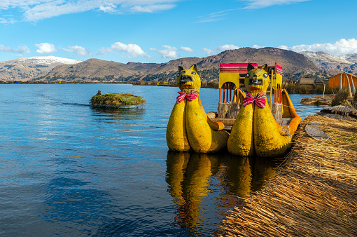 Totora reed boats by the Uros indigenous floating islands with reed transport, Titicaca Lake, Peru.