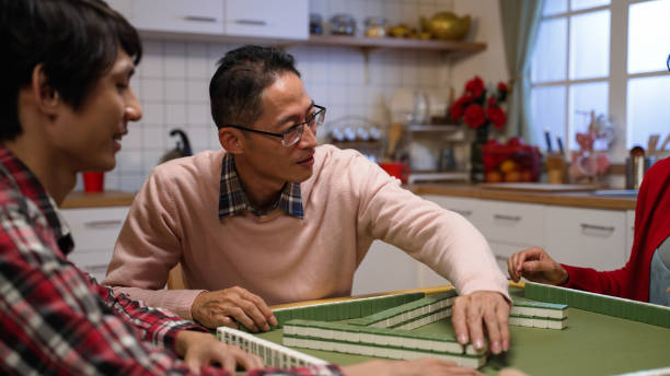 istock selective focus father picking and keeping a tile. then gesturing at son to play next after discarding another from his hand while playing mahjong at home during spring festival 1358178444