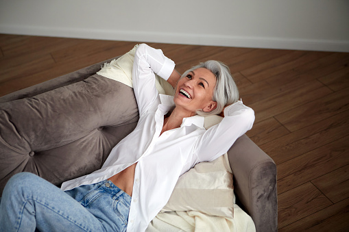 Mujer positiva de mediana edad riendo en el sofá photo