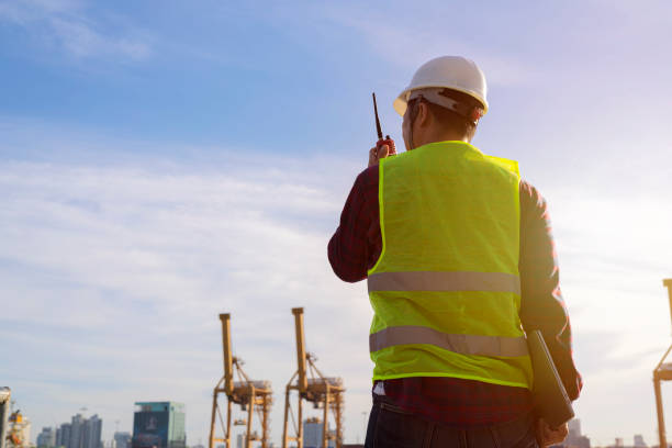 ingenieros y grúa.trabajador portuario sonriente sosteniendo radio y fondo de barco - freight transportation audio fotografías e imágenes de stock