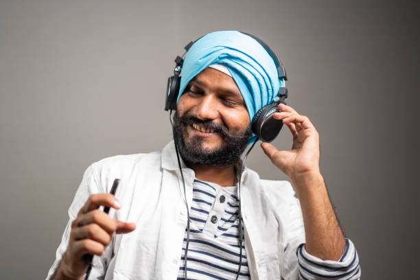 Cheerful young sikh man dancing while listening music on Headphone by using mobilephone- concept of joyful emotion and Happiness Cheerful young sikh man dancing while listening music on Headphone by using mobile phone- concept of joyful emotion and Happiness. web radio stock pictures, royalty-free photos & images