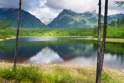 A beautiful forest lake against the background of the Kodar mountain system. Trans-Baikal Territory National Park Kodar.