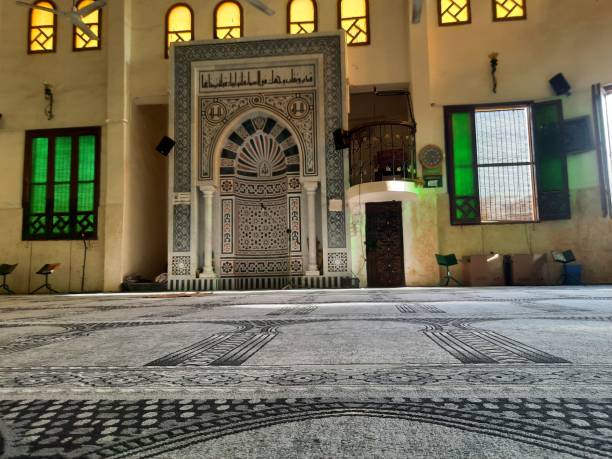 un interior de mezquita, una mezquita desde el interior a la luz del día con alfombras, ventanas de colores y un mihrab - alquibla fotos fotografías e imágenes de stock