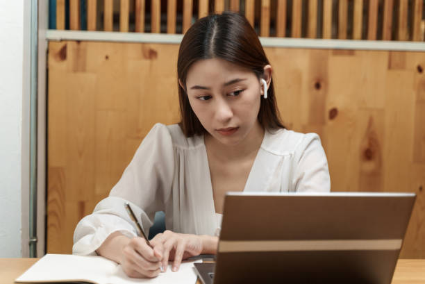 istock Attractive young Asian female student looking at laptop while studying online course. 1358186186
