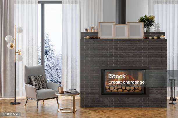 Luxury Living Room Interior With Armchair Burning Fireplace And Snow View From The Window Stock Photo - Download Image Now
