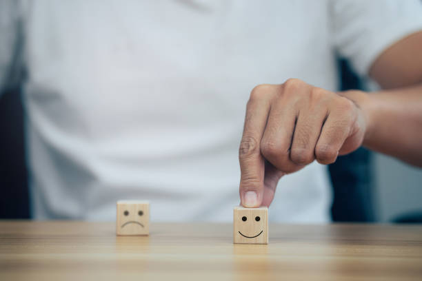 istock Closeup man choose smiley face and blurred sad face icon on wood cube. 1358188467