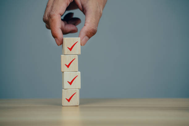 istock Closeup hands putting wooden block cube with icon check mark 1358189282