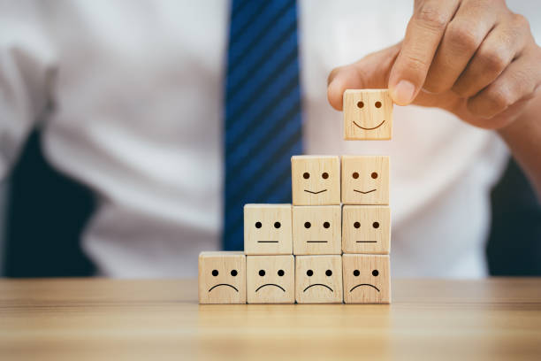 istock Closeup hands holding smiley face icon on wooden cube 1358189325