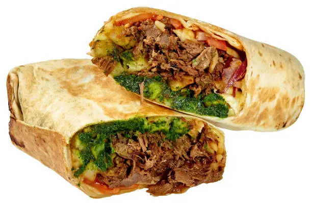 Delicious traditional Mexican birria burrito with stewed beef, french fries, mozzarella, onions, tomatoes and spicy green chimichurri sauce wrapped in grilled tortilla