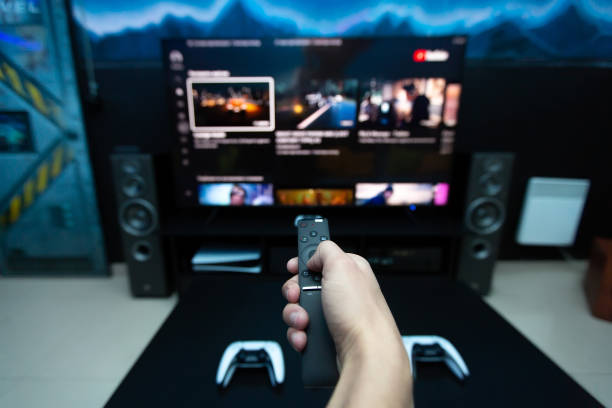 istock Close-up of a hand with a remote control from the console, choosing a computer game on a large TV. 1358190228