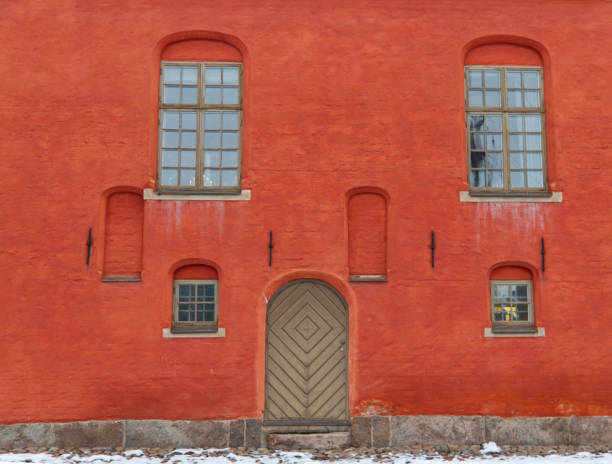 istock Red wall of a random stone building with a window on it 1358191162