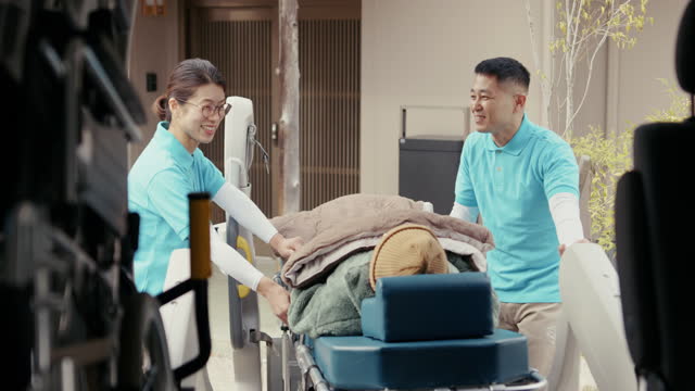 MS- Care assistants loading a senior patient into a care taxi