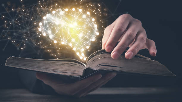 istock Man holding book with a human glowing brain. 1358191220