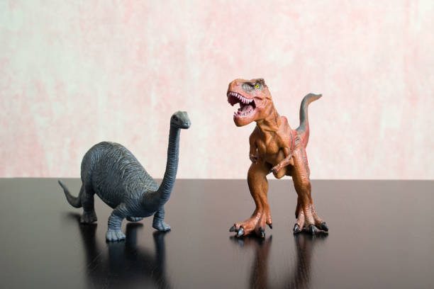 istock Two toy dinosaurs on a wooden table 1358192159