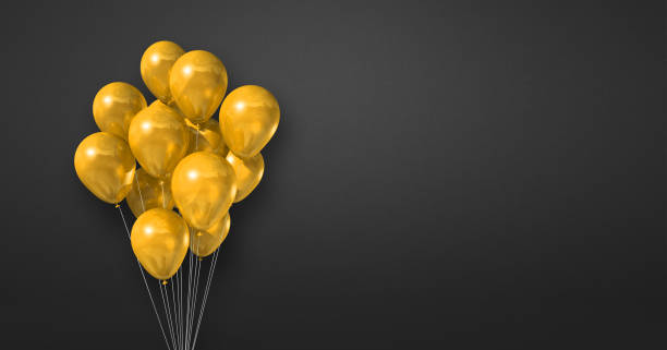 istock Yellow balloons bunch on a black wall background. Horizontal banner. 1358195627