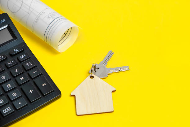 istock Calculator House Plan Drawing and Apartment Keys on a Yellow Background 1358195804