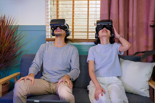 Couple are playing game with vr glasses. Leisure activity at home and technology concept.