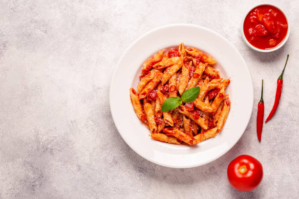 istock Classic italian pasta penne alla arrabiata with fresh basil on a light background, top view 1358199978