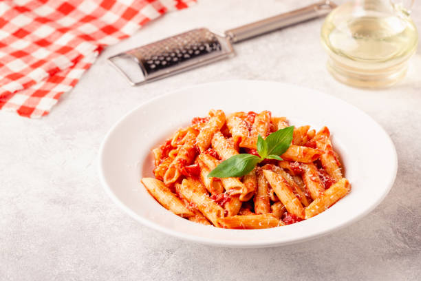 istock Classic italian pasta penne alla arrabiata with fresh basil on a light background, selective focus 1358200172