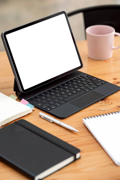 istock Blank screen portable tabet with magic keyboard on wooden table. 1358201011