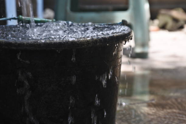 istock water spills from black bucket. full does not fit anymore. overload 1358201035