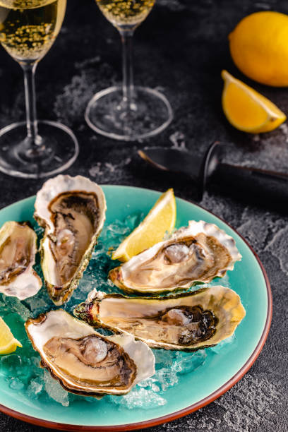 istock Opened fresh oysters on a blue plate, served with lemon and ice. 1358201213