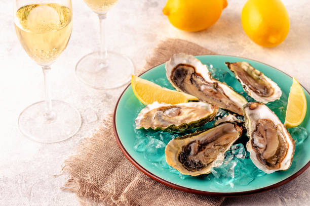 istock Opened fresh oysters on a blue plate, served with lemon and ice. 1358201214