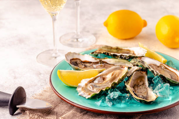 istock Opened fresh oysters on a blue plate, served with lemon and ice. 1358201323