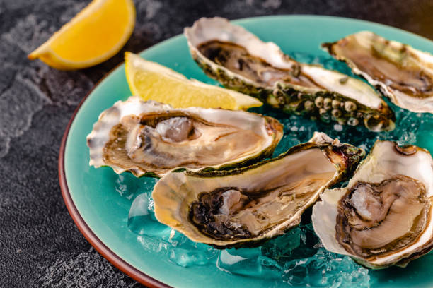 istock Opened fresh oysters on a blue plate, served with lemon and ice. 1358201500