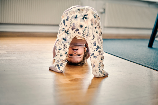 World upside down. Girl crawling on floor looking at camera