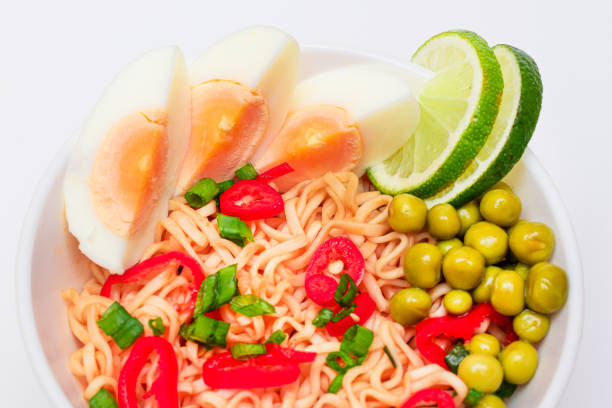 Beautiful Noodle Dish with Green Pea, Eggs, Red Hot Pepper, Greens and Lime on White Background. Instant Noodles