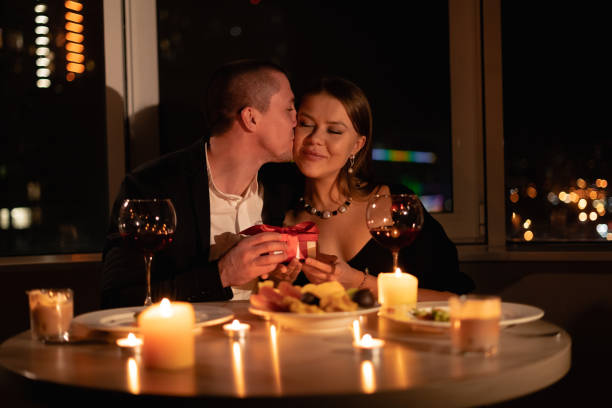 istock Romantic candlelight dinner for two, Valentine's Day date, authentic couple having dinner, a man giving a gift to woman, romantic family relationship 1358205014