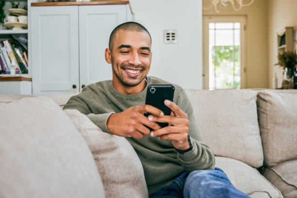 shot of a young man using his smartphone to send text messages - vrije tijd fotos stockfoto's en -beelden