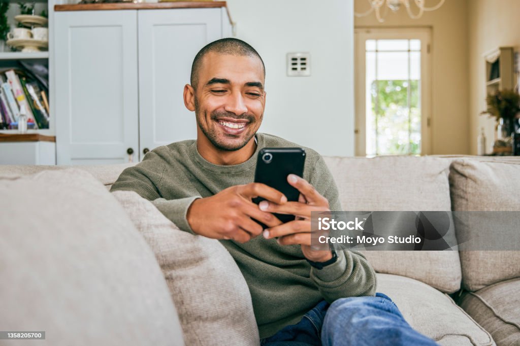 Shot of a young man using his smartphone to send text messages Your smile brightens my day Men Stock Photo