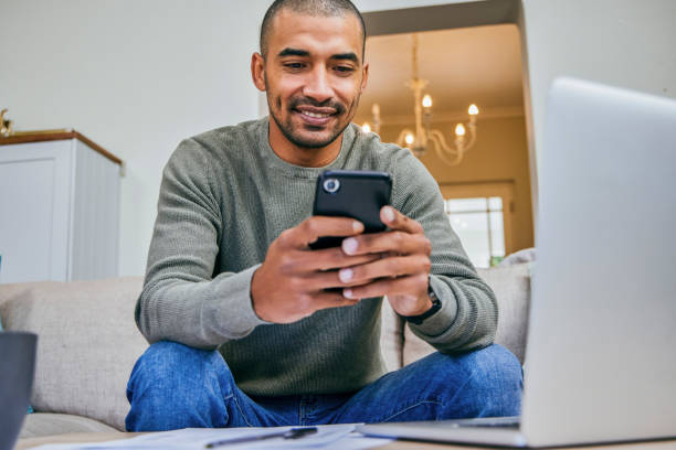 istock Shot of a young man using his smartphone and laptop while working from home 1358205939