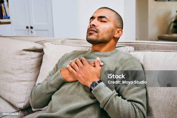Shot Of A Young Man Experiencing Chest Pains At Home Stock Photo - Download Image Now