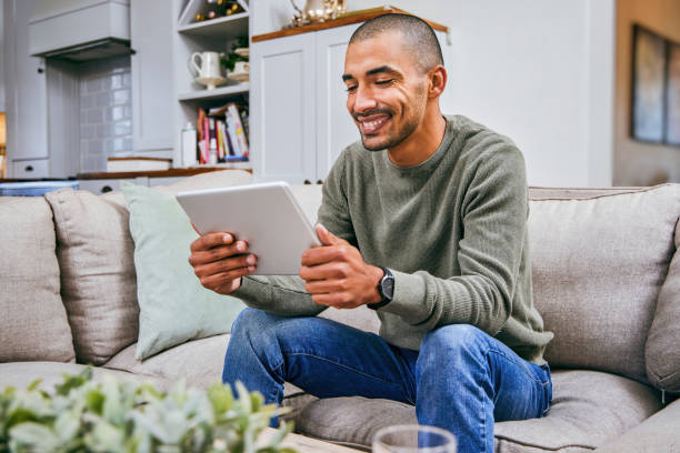 istock Shot of a young man using his digital tablet at home 1358207606