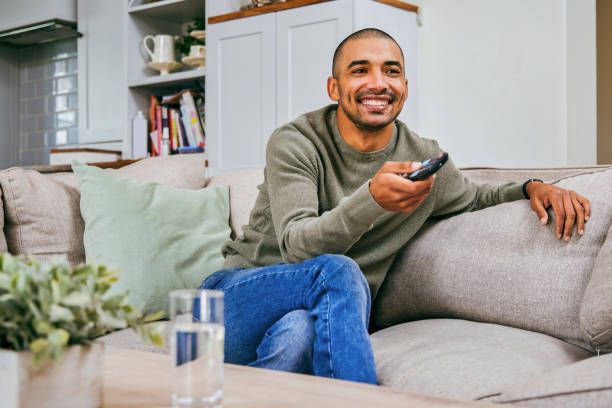 istock Shot of a young man relaxing at home watching TV 1358207607