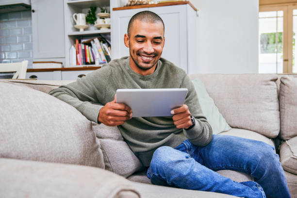 istock Shot of a young man using his digital tablet at home 1358207608
