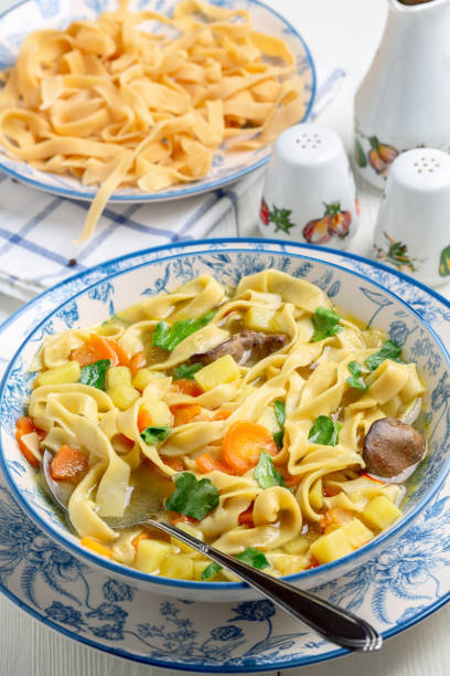 Homemade noodles with chicken broth and vegetables. Bowl of homemade egg noodles and vegetables is served with fresh parsley. Concept of healthy homemade food. cooked selective focus vertical pasta stock pictures, royalty-free photos & images