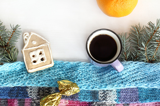 flat lay small espresso cup and gingerbread house with fir branches and knitted scarves on the table top view. warming home atmosphere of winter weekdays