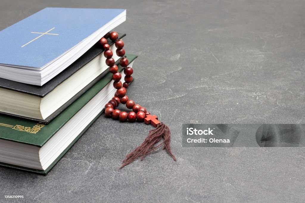 Books and rosary on black. Cross on cover of top book. Books and rosary on black. Cross on cover of top book. Copy space. Backgrounds Stock Photo