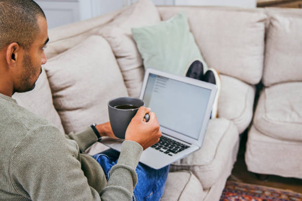 istock Shot of a man using his laptop to work from home while enjoying a cup of coffee 1358211531