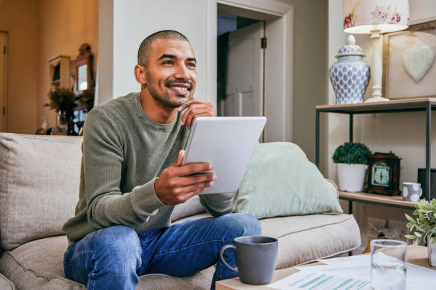 istock Shot of a young man using his digital tablet while relaxing at home 1358211814